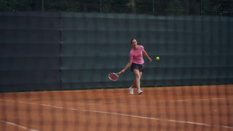 Nahaufnahme-Eines-Tennisplatzgitters,-Im-Hintergrund-Schlägt-Eine-Frau-Einen-Ball